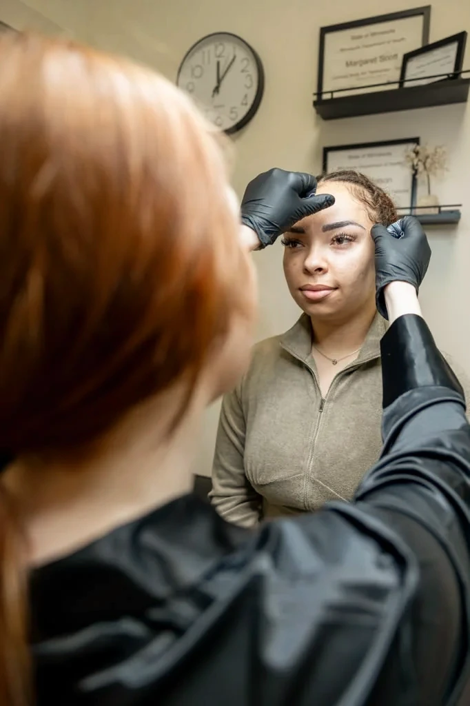 Instructor mapping a brow shape on a live model during permanent makeup training